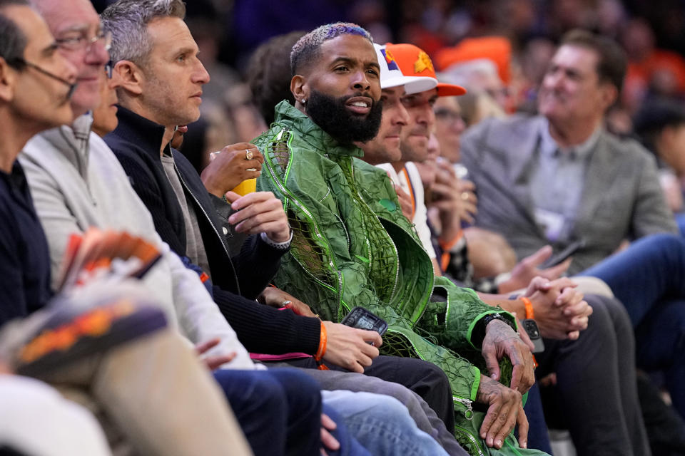 NFL football player Odell Beckham Jr., center, watches the Phoenix Suns and the Denver Nuggets compete during the second half of an NBA basketball game, Friday, March 31, 2023, in Phoenix. (AP Photo/Matt York)