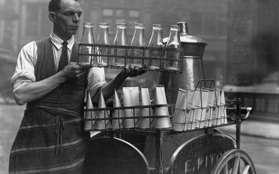 A milkman in the 1920s offering customers a choice between glass and paper containers - Fox Photos/Getty Images