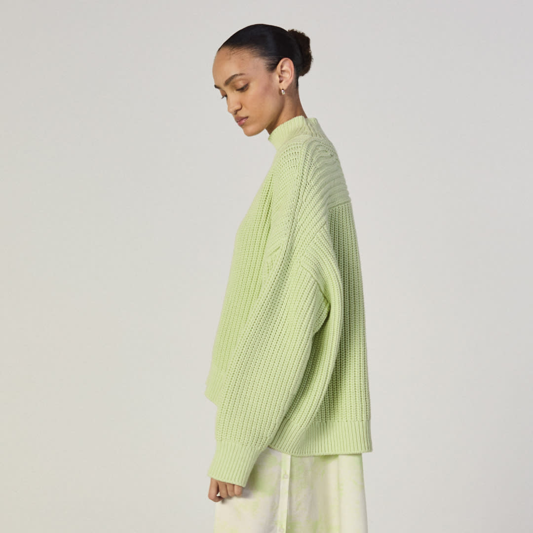  A model wears a green sweater and tie dye skirt from everlane. 