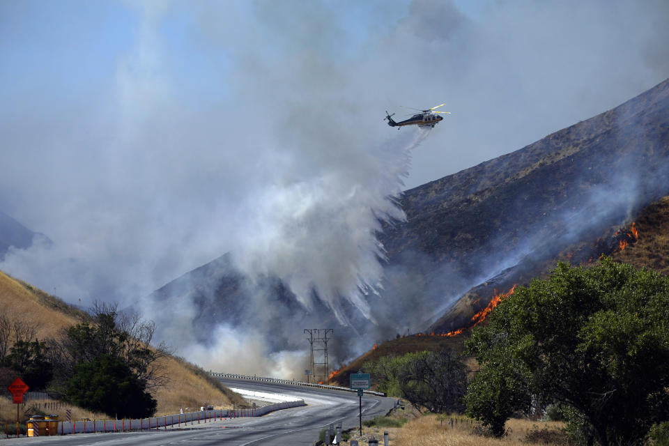 A helicopter drops water on the advancing Route Fire over the closed-off interstate 5 Wednesday, Aug. 31, 2022, in Castaic, Calif. (AP Photo/Marcio Jose Sanchez)