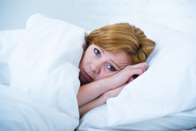 young attractive woman in sad and depressed face expression with eyes wide open lying in bed looking sick and unable to sleep su