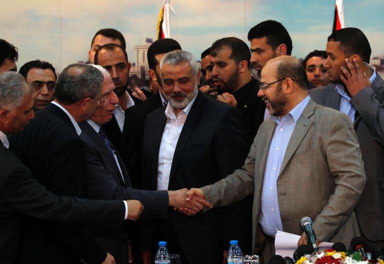 Palestinian Fatah envoy Azzam al-Ahmed (left) shakes hands with Hamas deputy leader Musa Abu Marzuk (right) in the presence of Hamas prime minister Ismail Haniya (centre) after signing a reconciliation agreement in Gaza City, on April 23, 2014