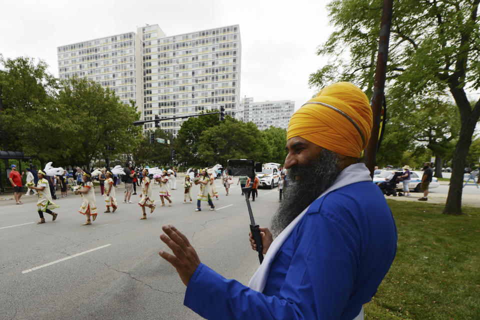Members of the Cristo Rey Parish perform as a man films during the Parliament of World Religion Parade of Faiths, Sunday, Aug. 13, 2023, in Chicago. (AP Photo/Paul Beaty)