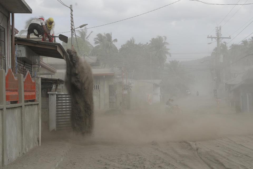 Residents shovel volcanic ash from the roof of their homes at a village near Taal volcano where people have evacuated to safer grounds in Agoncillo, Batangas province, southern Philippines on Saturday Jan. 18, 2020. Local authorities have allowed some residents to return to their homes for a few hours in the morning to retrieve belongings and feed their pets or farm animals. The Taal volcano near the Philippine capital emitted more ash clouds Saturday, posing the threat of another eruption. (AP Photo/Aaron Favila)