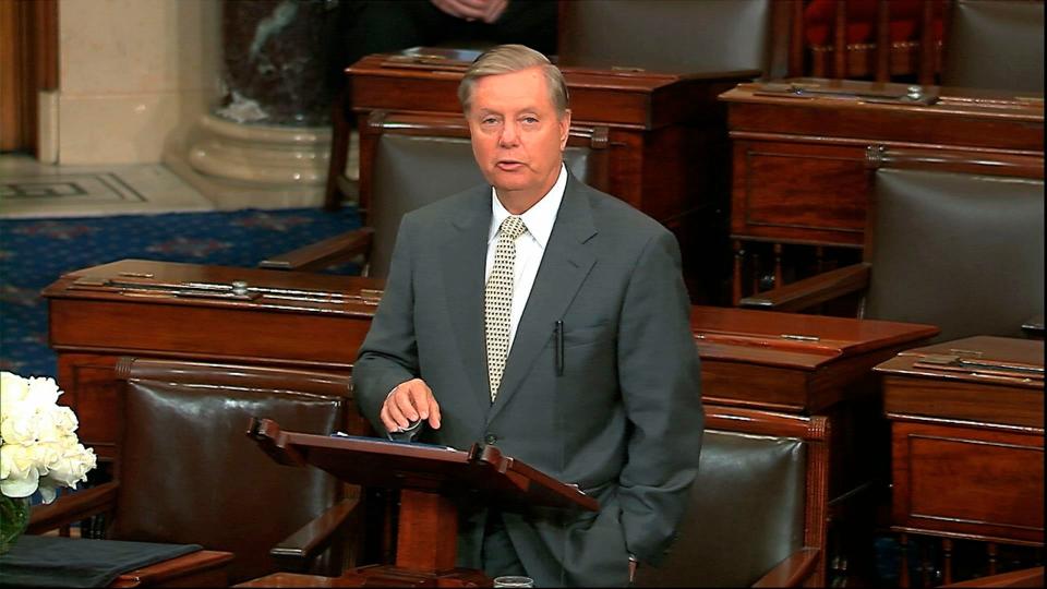 In this image from Senate Television, Sen. Lindsey Graham, R-S.C., speaks on the Senate floor at the Capitol in Washington,, next to the desk of Sen. John McCain, R-Ariz., draped in black with a bowl of white roses sitting on it on Aug. 28, 2018.