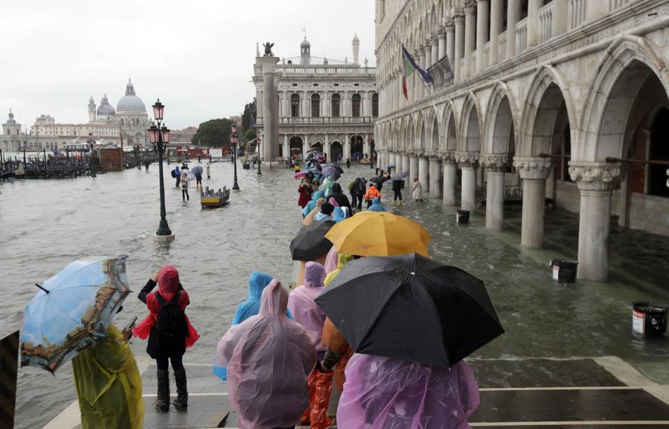People walk on catwalk set up on the occasion of a high tide, in a flooded Venice, Italy, Tuesday, Nov. 12, 2019. (Photo: Luca Bruno/AP)
