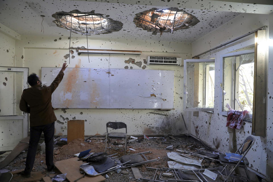 FILE - In this Nov. 3, 2020 file photo, a man reaches up in a damaged room at Kabul University following a deadly attack, in Kabul, Afghanistan, Tuesday, Nov. 3, 2020. It’s not just dramatic attacks like this one that killed dozens at the university last year, frequent bombings have everyone on edge. Afghanistan is supposed to be moving toward peace, but Kabul's residents fear the turmoil is a sign it is instead entering yet another phase in decades of war. (AP Photo/Rahmat Gul, File)