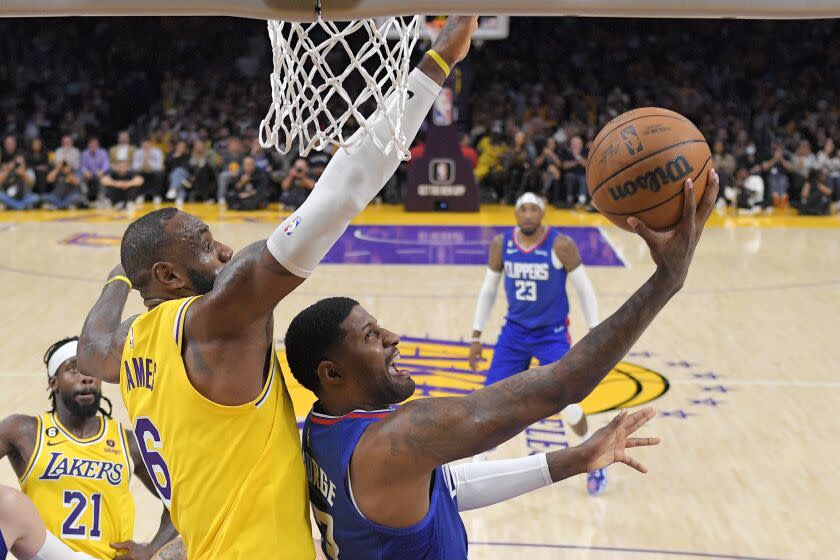 Los Angeles Clippers guard Paul George, right, shoots as Los Angeles Lakers forward LeBron James defends