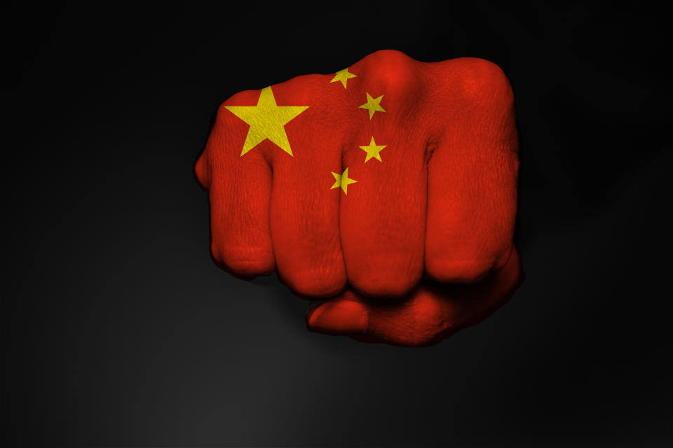 Low key picture of a fist painted in colors of a China flag on a black backround