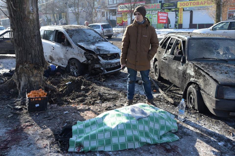 A man stands next to a body of his mother killed as a result of a missile strike in Donetsk (AFP via Getty Images)