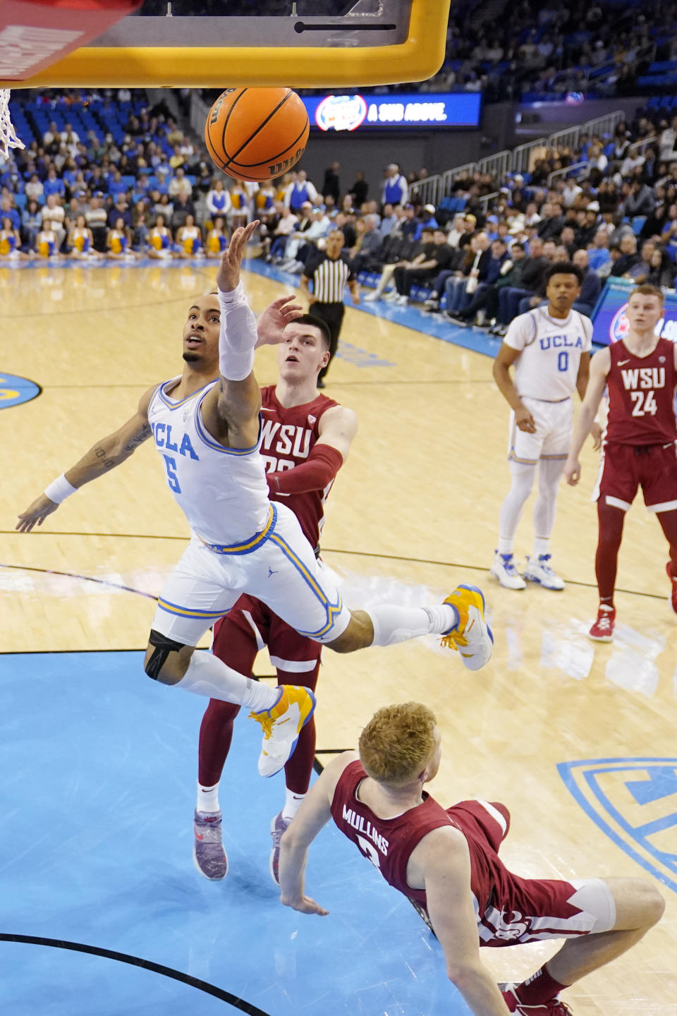 UCLA guard Amari Bailey, left, shoots as Washington State guard Jabe Mullins, below, falls and forward Andrej Jakimovski defends during the first half of an NCAA college basketball game Saturday, Feb. 4, 2023, in Los Angeles. (AP Photo/Mark J. Terrill)