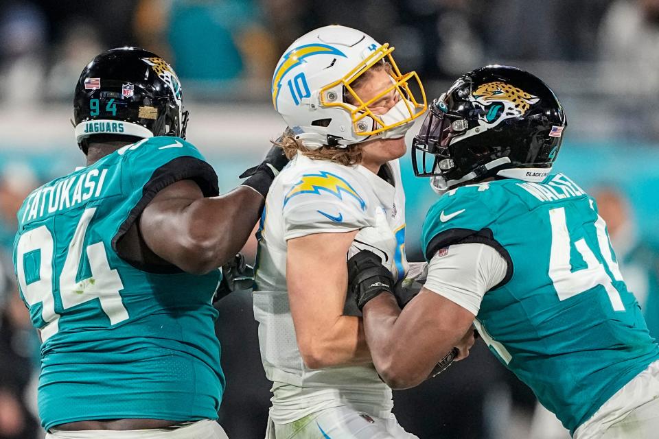 Chargers QB Justin Herbert (10) takes a hit from Jaguars LB Travon Walker (44) Saturday night.