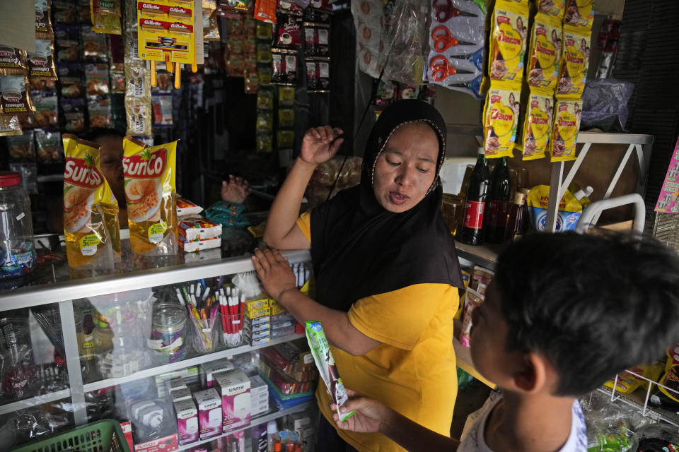 Asiyah talks to her son Muhammad Ibnu Rosihin as they shop for groceries at convenience store near their house in Semarang, Central Java, Indonesia, Sunday, Sept. 4, 2022. The family eventually abandoned their flooding home in another village and moved to drier land, becoming climate migrants as many of their neighbors had before them. Their story illustrates how climate change can play a major factor in forcing people to migrate. (AP Photo/Dita Alangkara)