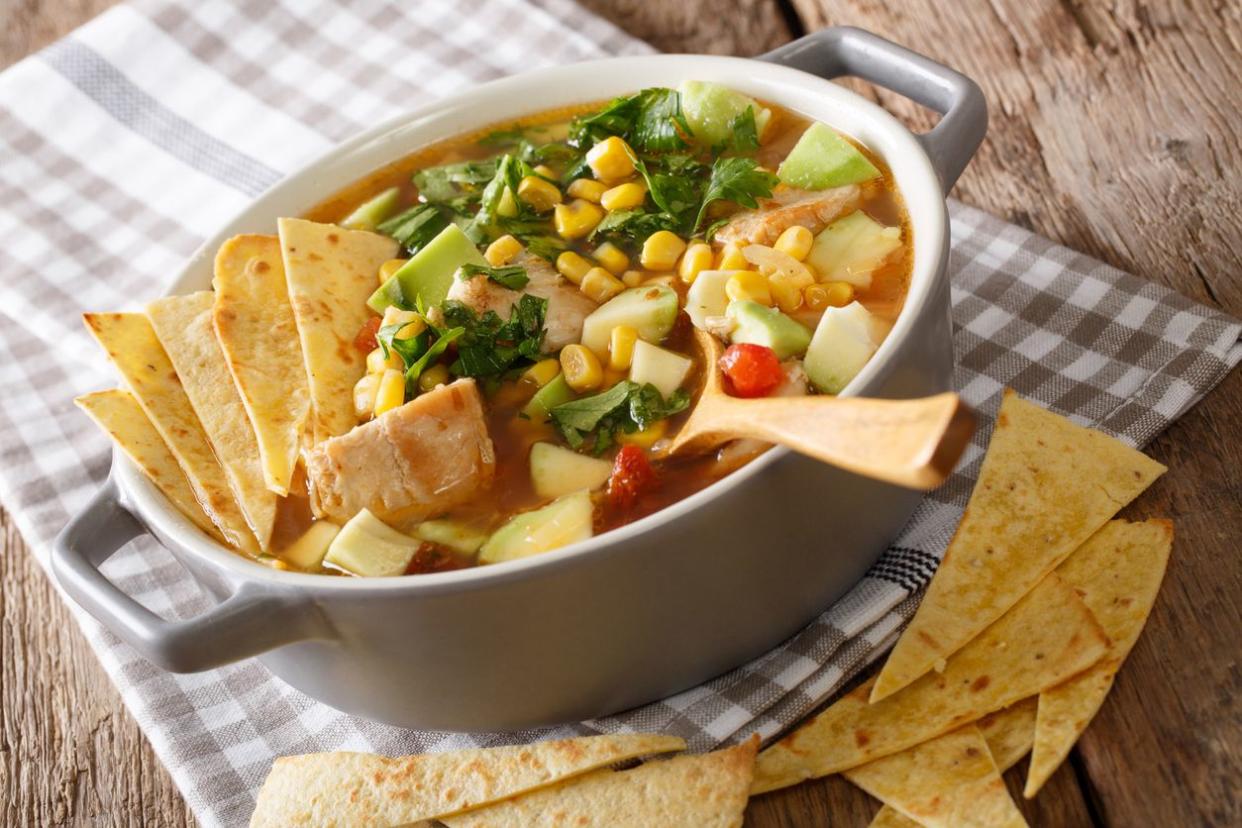 Mexican tortilla soup with chicken and vegetables close-up in a saucepan on a table. horizontal