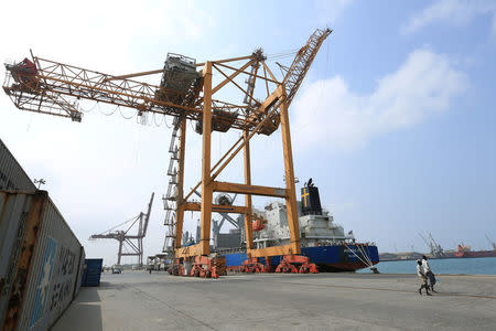 Workers walk past cranes damaged by air strikes at the port of Hodeida, Yemen April 1, 2018. REUTERS/Abduljabbar Zeyad