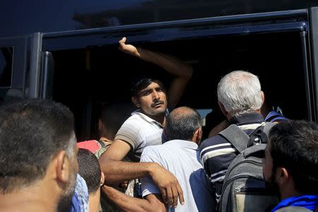 A migrant (C) is squeezed among refugees and other migrants trying to get on a bus following their arrival onboard the Eleftherios Venizelos passenger ship at the port of Piraeus near Athens, Greece, September 4, 2015. REUTERS/Alkis Konstantinidis