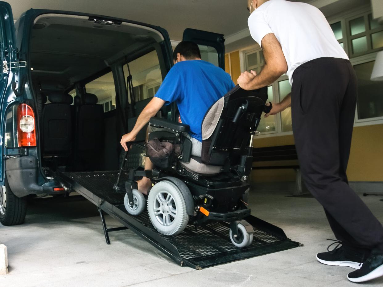 Man on wheelchair using vehicle ramp