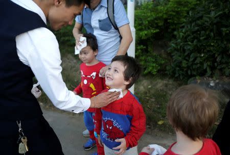 A real estate salesman wipes the sweat off of An Zhifei, one of An Hui's and Ye Jianbin's three sons, during a visit to a villa on sale in Xishuangbanna, Yunnan province, China December 6, 2018. An and his partner are fathers of triplets who were conceived with the help of a German egg donor. REUTERS/Jason Lee