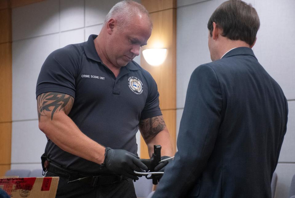 Crime Scene Technician James Farrell, left, and prosecutor Matthew Gordon secure a firearm that is being introduced as evidence during the trial of James Blackmon at the Escambia County Courthouse in Pensacola on Thursday, July 21, 2022.  Blackmon is on trial for alledgedly killing his adult stepson and attempting to kill his stepson's girlfriend.