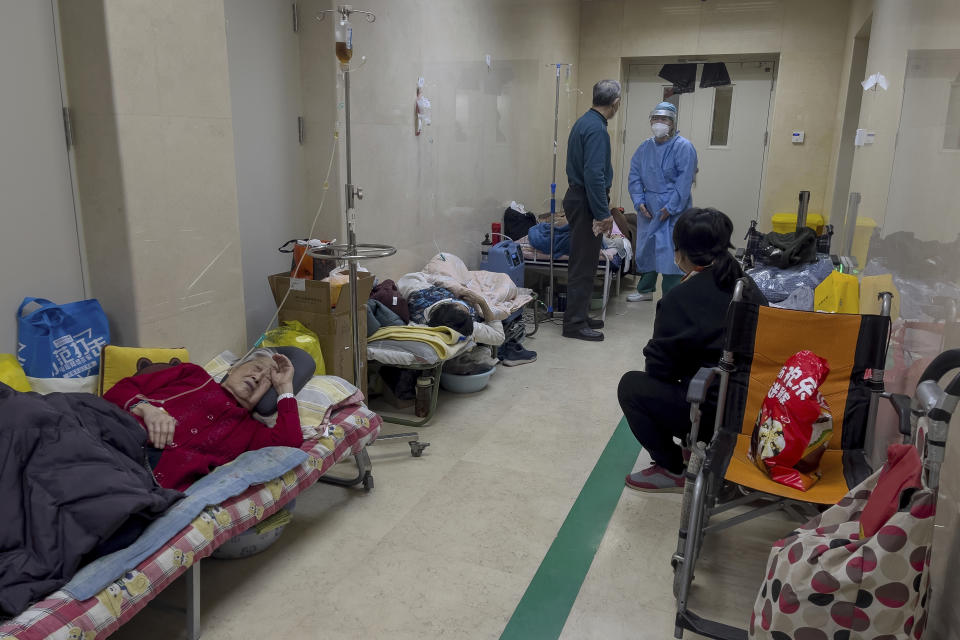 A man talks to a medical worker as elderly patients rest along a corridor of the emergency ward to receive intravenous drips at a hospital in Beijing, Thursday, Jan. 5, 2023. Patients, most of them elderly, are lying on stretchers in hallways and taking oxygen while sitting in wheelchairs as COVID-19 surges in China's capital Beijing. (AP Photo/Andy Wong)