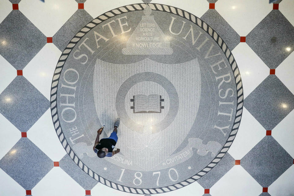 FILE—In this file photo from May 18, 2019, pedestrians pass through The Ohio State University's student union, in Columbus, Ohio. Dozens more men are suing Ohio State over the university's failure to stop sexual abuse and misconduct decades ago by team doctor Richard Strauss. They echo claims filed previously by over 400 men, many of whom allege they were groped during medical exams. The newest claims were filed in federal court ahead of Monday, May 17, 2021 which marked two years since OSU released a law firm report that concluded university employees knew of concerns about Strauss but didn't stop him. (AP Photo/John Minchillo, File)