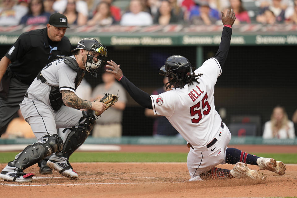 Cleveland Guardians' Josh Bell (55) slides home next to Chicago White Sox catcher Yasmani Grandal, left, who made the tag during the fourth inning of a baseball game Tuesday, May 23, 2023, in Cleveland. (AP Photo/Sue Ogrocki)