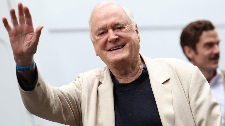 British actor John Cleese waves as he arrives for a photocall promoting the theatrical remake of his 1975 television program “Fawlty Towers” at the Apollo Theatre in London, Britain, May 2, 2024