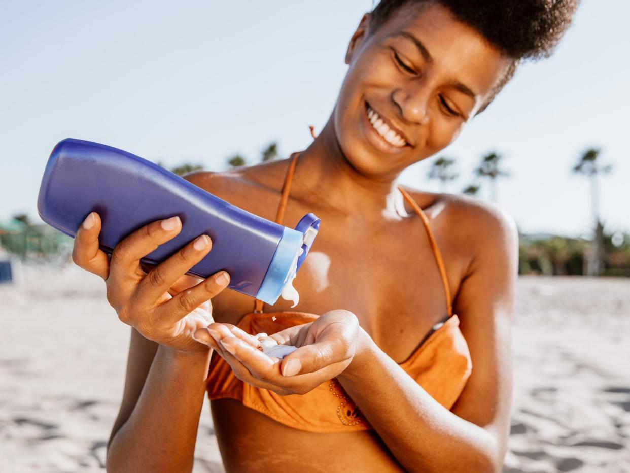 Woman sunbathing and applying suntan lotion at the beach