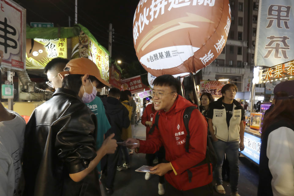 Hong Tsun-ming, center, a Taiwanese of Hong Kong descent, distributes election flyers to Taiwanese people at a night market in Taichung city, Central Taiwan, on Nov. 30, 2023. As Taiwan’s presidential election approaches, many immigrants from Hong Kong, witnesses to the alarming erosion of civil liberties at home, are supporting the ruling Democratic Progressive Party. (AP Photo/Chiang Ying-ying)