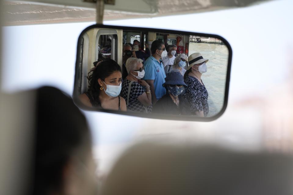 Tourists and citizens are reflected in a mirror as they stand in a public transport boat, in Venice, Italy, Thursday, June 17, 2021. After a 15-month pause in mass international travel, Venetians are contemplating how to welcome visitors back to the picture-postcard canals and Byzantine backdrops without suffering the indignities of crowds clogging its narrow alleyways, day-trippers perched on stoops to imbibe a panino and hordes of selfie-takers straining for a spot on the Rialto Bridge or in front of St. Mark’s Basilica. (AP Photo/Luca Bruno)