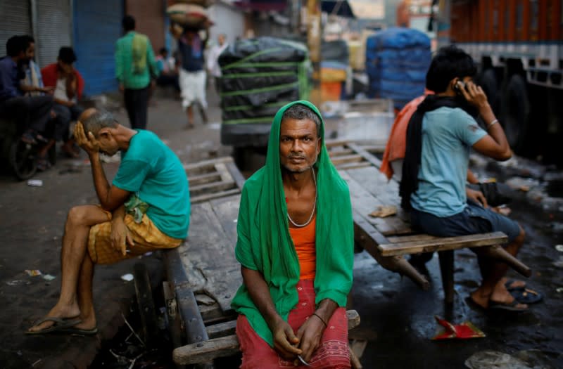 FILE PHOTO: Migrant labourers sit on a handcart as they wait for work at a wholesale market in the old quarters of Delhi