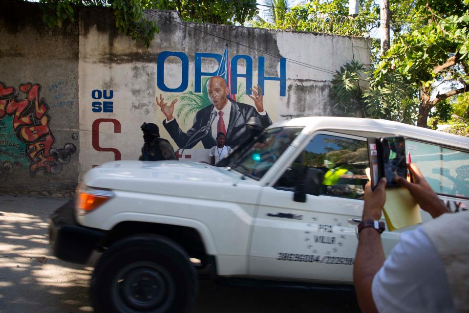 An ambulance carrying the body of Haiti's President Jovenel Moise drives past a mural featuring him near the leader’s residence where he was killed by gunmen in the early morning in Port-au-Prince, Haiti, Wednesday, July 7, 2021. Claude Joseph, the interim prime minister, confirmed the killing and said the police and military were in control of security in Haiti.