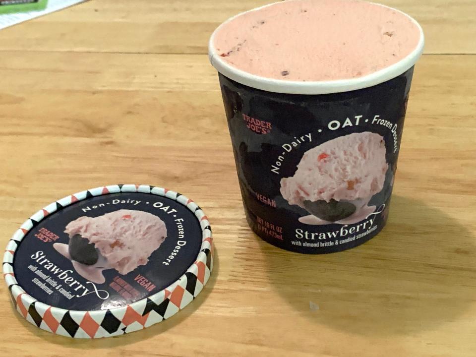 Black carton of Trader Joe's pink strawberry oat ice cream on wood table