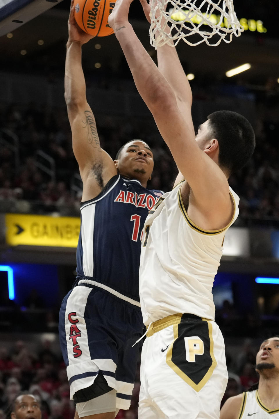 Arizona forward Keshad Johnson, left, dunks in front of Purdue center Zach Edey in the first half of an NCAA college basketball game in Indianapolis, Saturday, Dec. 16, 2023. (AP Photo/AJ Mast)