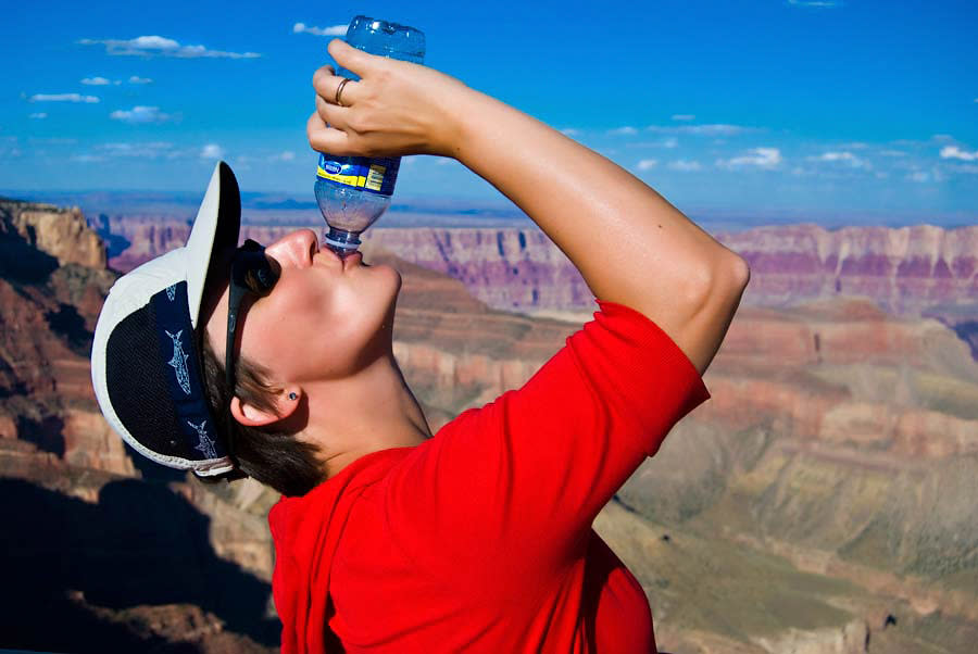 hiker drinking bottled water in desert