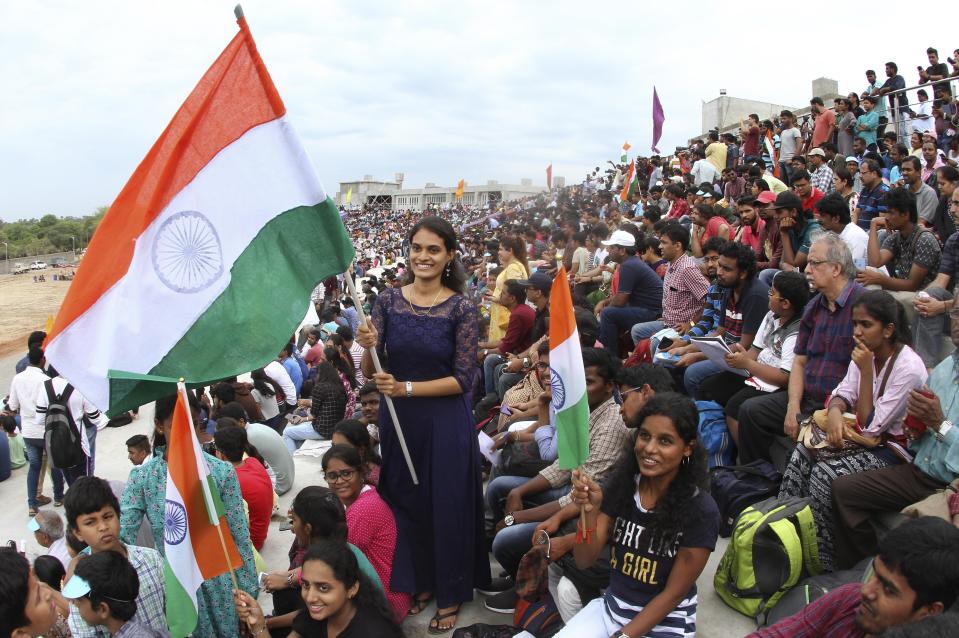 People wave the Indian flag as they gather to watch the launch of Indian Space Research Organization (ISRO)'s Geosynchronous Satellite launch Vehicle (GSLV) MkIII carrying Chandrayaan-2 from Satish Dhawan Space center in Sriharikota, India, Monday, July 22, 2019. India successfully launched an unmanned spacecraft to the far side of the moon on Monday, a week after aborting the mission due to a technical problem. (AP Photo)