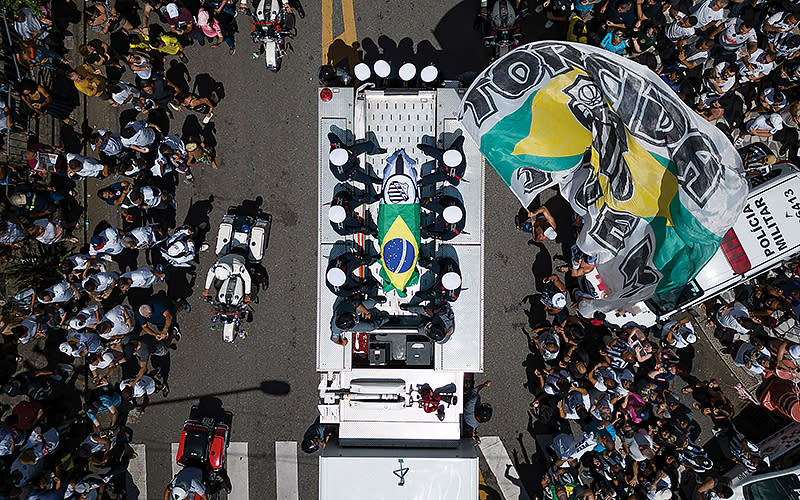 The casket of late Brazilian soccer great Pelé is draped in the Brazilian and Santos FC soccer club flags as his remains are transported from Vila Belmiro stadium, where he laid in state, to the cemetery during his funeral procession in Santos, Brazil, on Jan. 3. <em>Associated Press/Matias Delacroix</em>