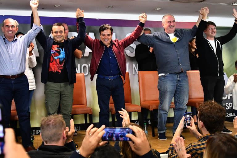 El ganador que no está en la boleta: a Carlos Rovira (centro) le levantan la mano el gobernador actual, Oscar Herrera Ahuad, y el ganador de las elecciones, Hugo Passalacqua