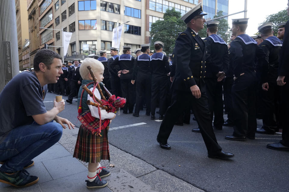 Eddie McMullen, 2, is dressed in a kilt and carries bagpipes as he watches sailors prepare for the Anzac Day parade in Sydney, Tuesday, April 25, 2023. (AP Photo/Rick Rycroft)