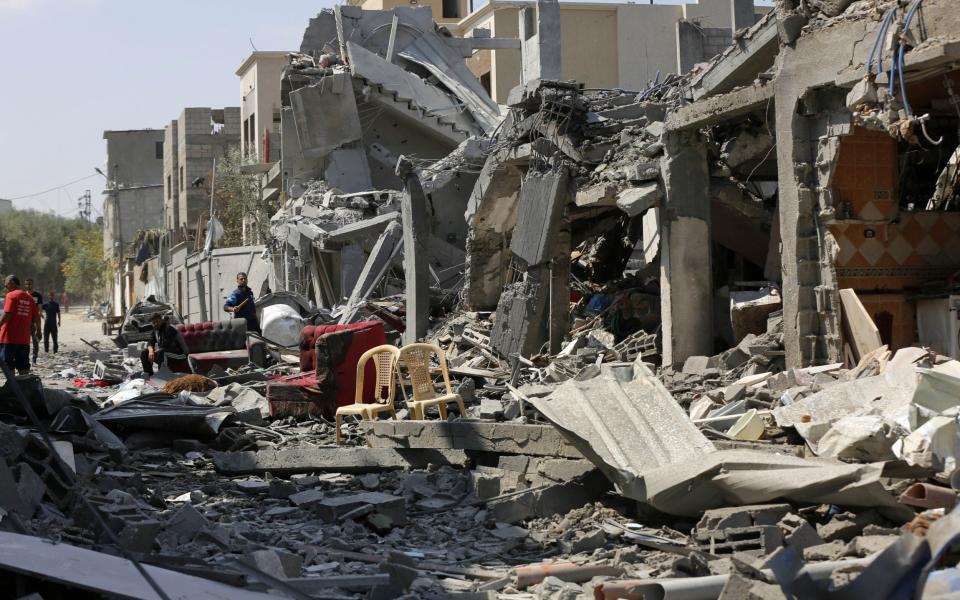 Palestinians inspect the destroyed buildings after the Israeli attack on Al-Maghazi refugee camp