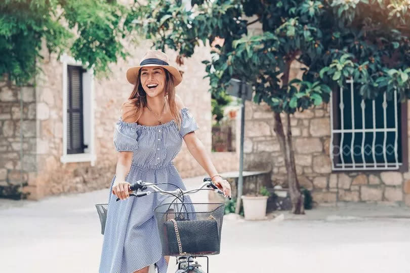 Smiling young woman riding a bikeG