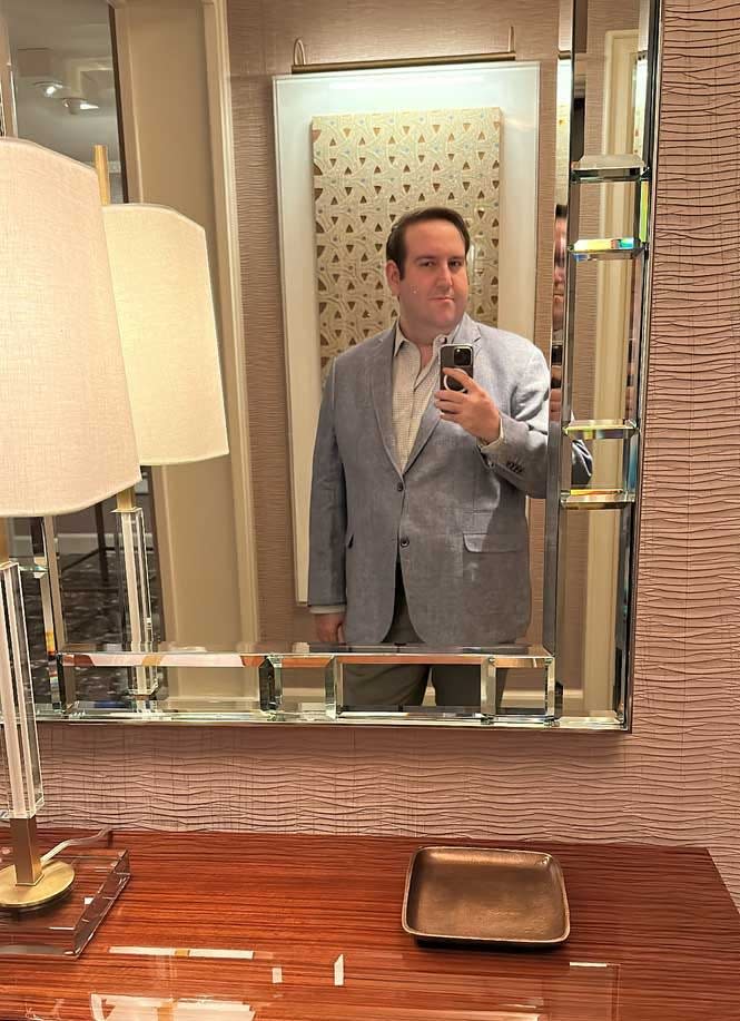 A man taking a selfie in a mirror, wearing a suit.