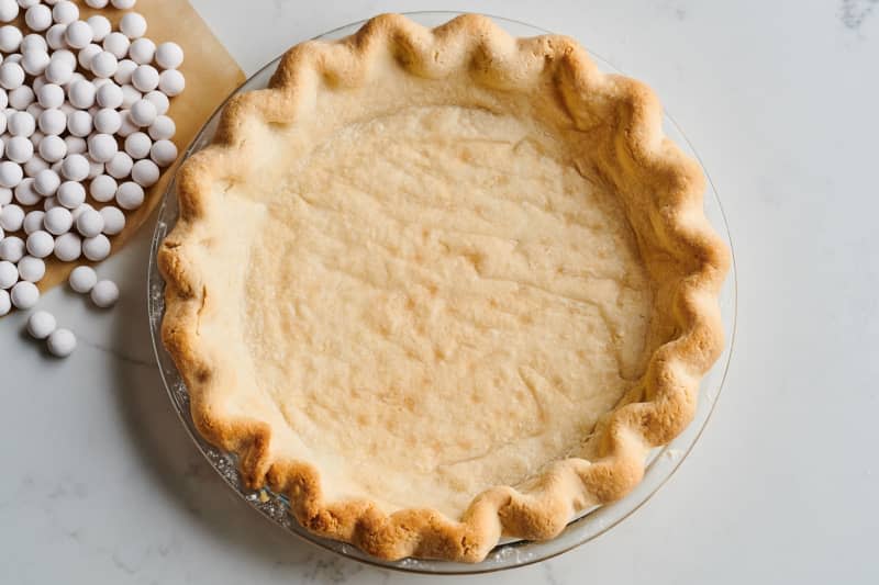 pie crust in tin sits next to ceramic weights