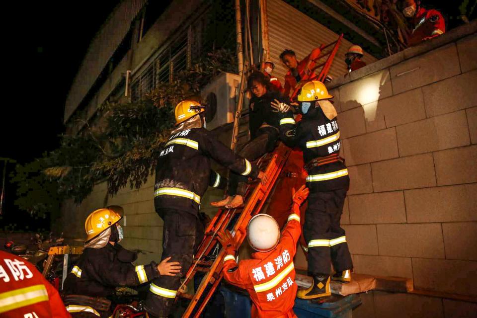 A woman (top of the ladder) is rescued from the rubble of a collapsed hotel in Quanzhou, in China's eastern Fujian province on March 7, 2020. - Around 70 people were trapped after the Xinjia Hotel collapsed on March 7 evening, officials said. (Photo by STR / AFP) / China OUT (Photo by STR/AFP via Getty Images)