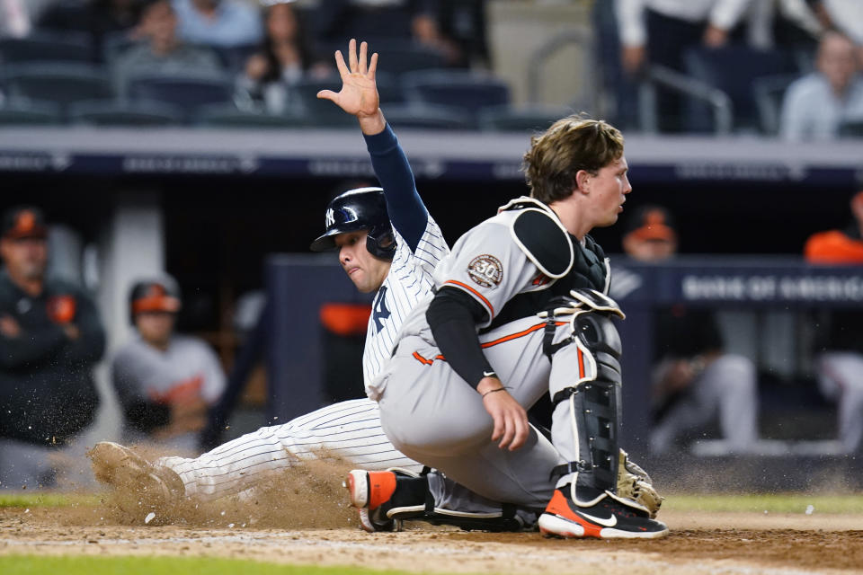 New York Yankees' Isiah Kiner-Falefa, rear, slides past Baltimore Orioles catcher Adley Rutschman to score on a single by Jose Trevino during the seventh inning of a baseball game Tuesday, May 24, 2022, in New York. (AP Photo/Frank Franklin II)