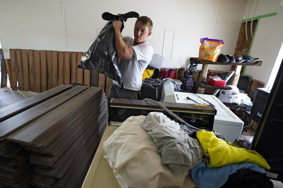 Jordan Cromer carries water logged trash out of his home Tuesday, Oct. 4, 2022, in North Port, Fla. Residents along Florida's west coast are cleaning up damage after Hurricane Ian made landfall last week. (AP Photo/Chris O'Meara)