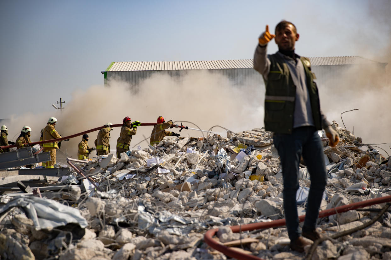 Firefighters extinguish a fire in the rubble of a factory in Turkey after a quake.