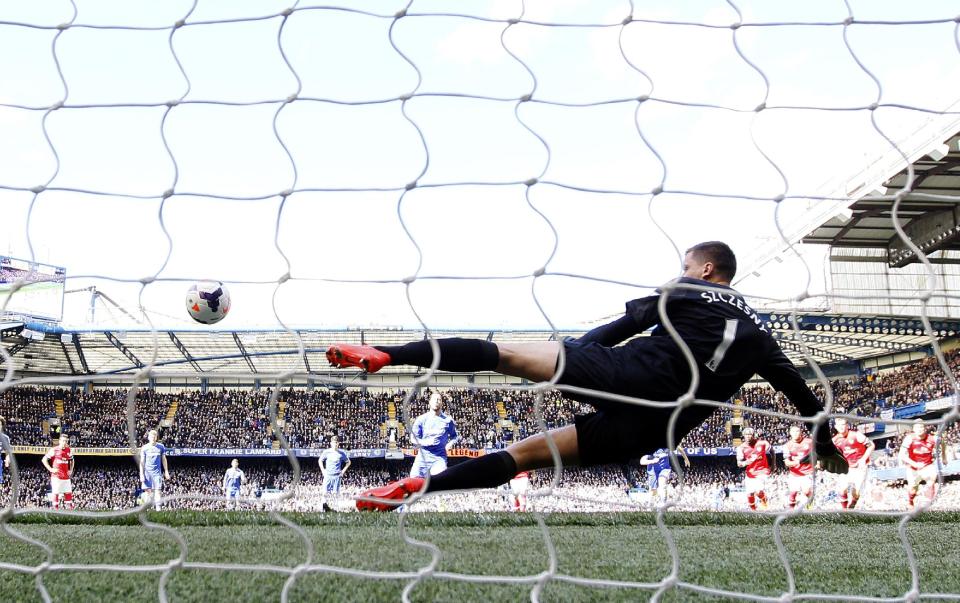 Chelsea's Eden Hazard, scores his sides third goal from the penalty spot past a diving Arsenal goalkeeper Wojciech Szczesny during their English Premier League soccer match between Chelsea and Arsenal at Stamford Bridge stadium in London, Saturday, March 22, 2014. (AP Photo/Alastair Grant)