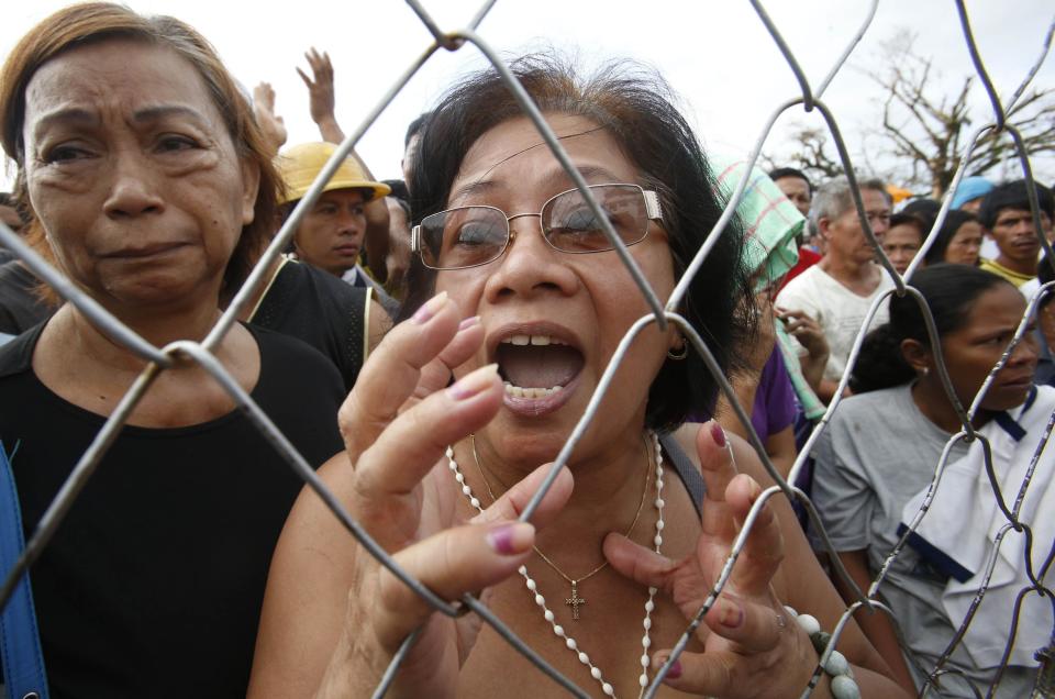 Typhoon victims ask for water and food from soldiers outside the gate of a government compound in Tacloban city