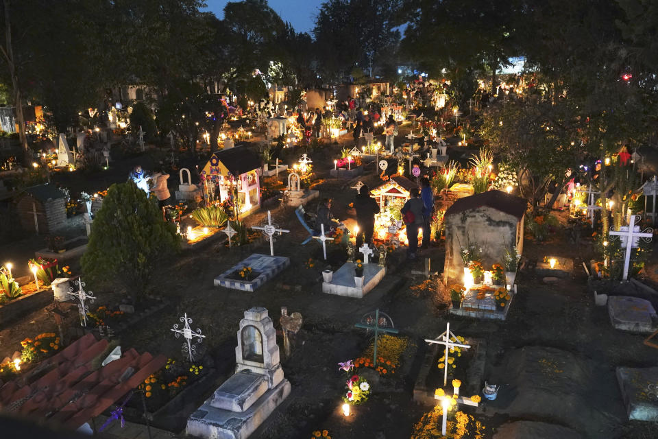 La gente se reúne en la sección de tumbas de niños dentro del cementerio de San Gregorio Atlapulco durante las festividades del Día de Muertos en las afueras de la Ciudad de México, la madrugada del miércoles 1 de noviembre de 2023. (AP Foto/Marco Ugarte)
